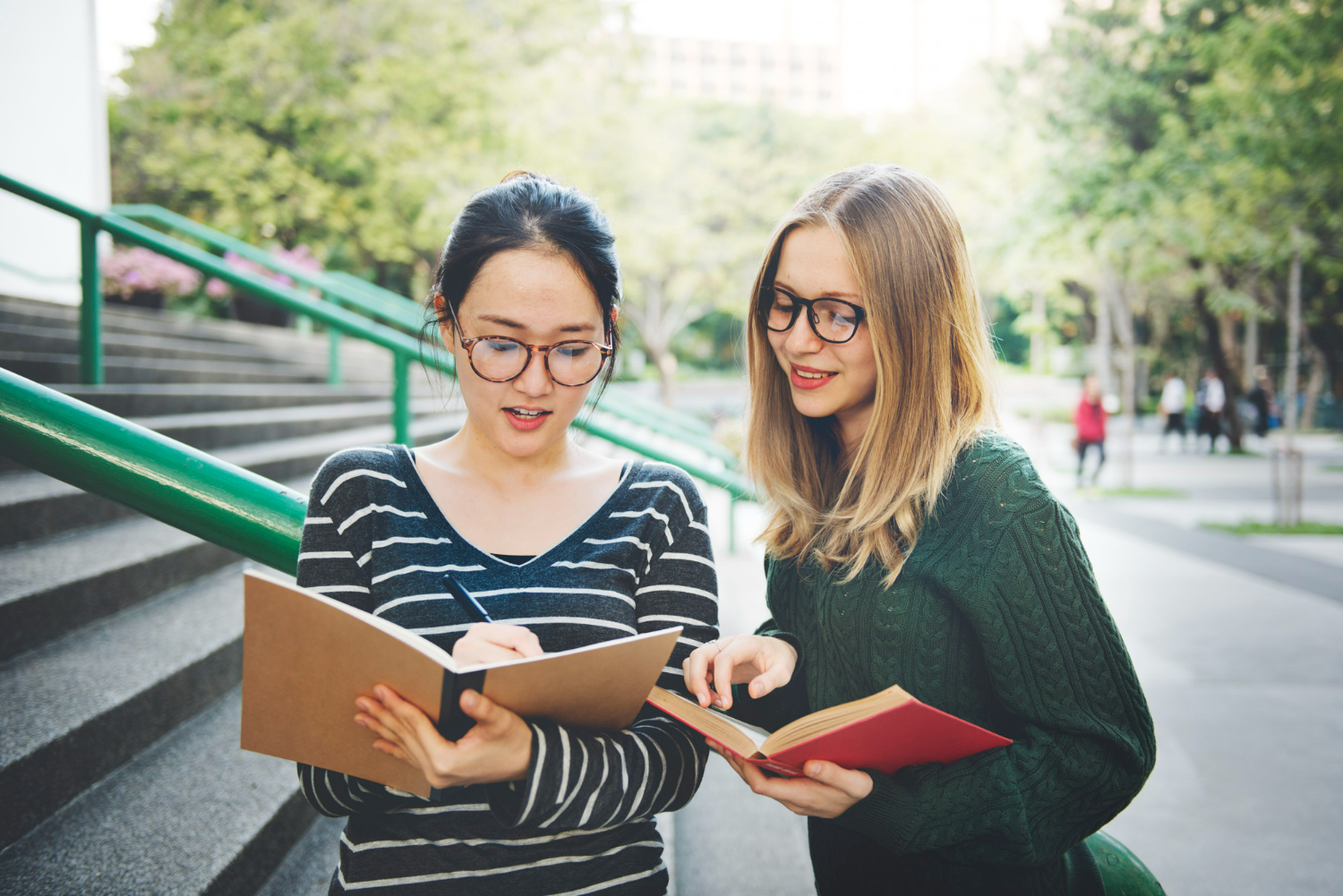 two girls looking at notes on university campus two girls looking at notes on university campus