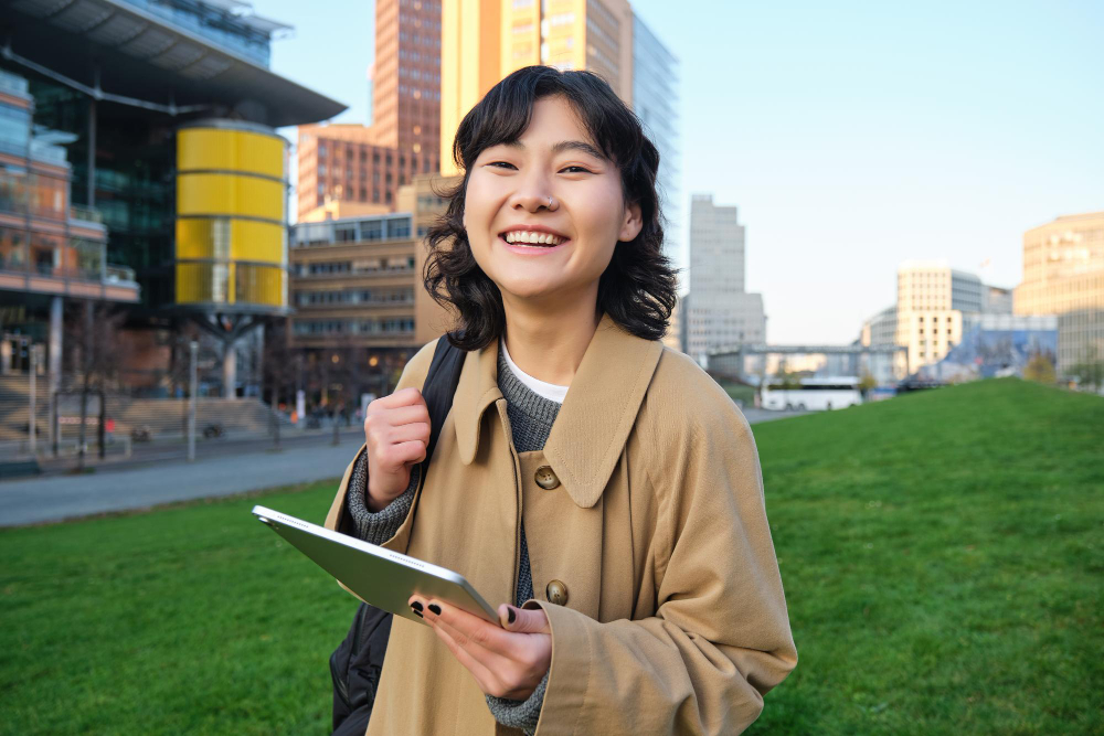 University student smiling while holding a tablet on campus