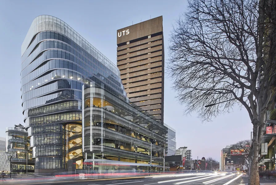 The UTS Sydney city campus at dusk, with the curved glass UTS Central building next to the brown UTS Tower