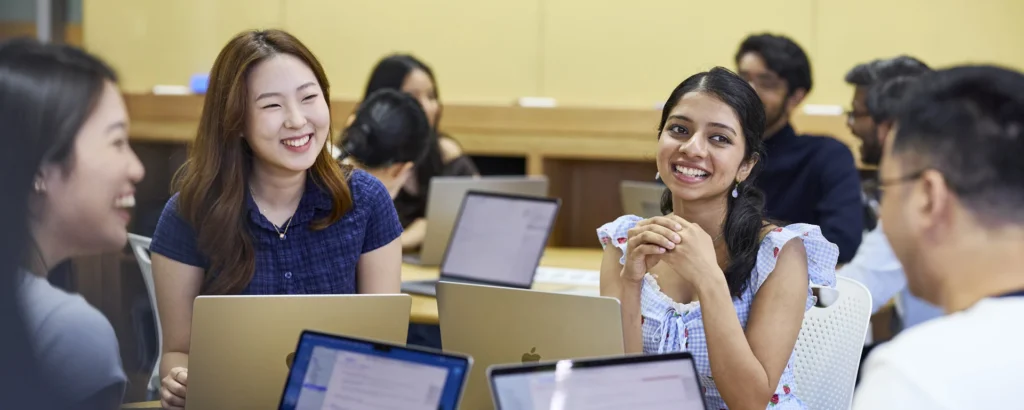 Smiling students with laptops working together in a class at UTS Sydney