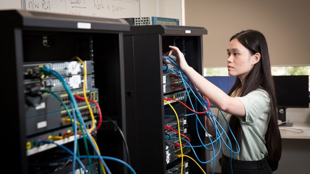 Computer science student working with network equipment at Adelaide University